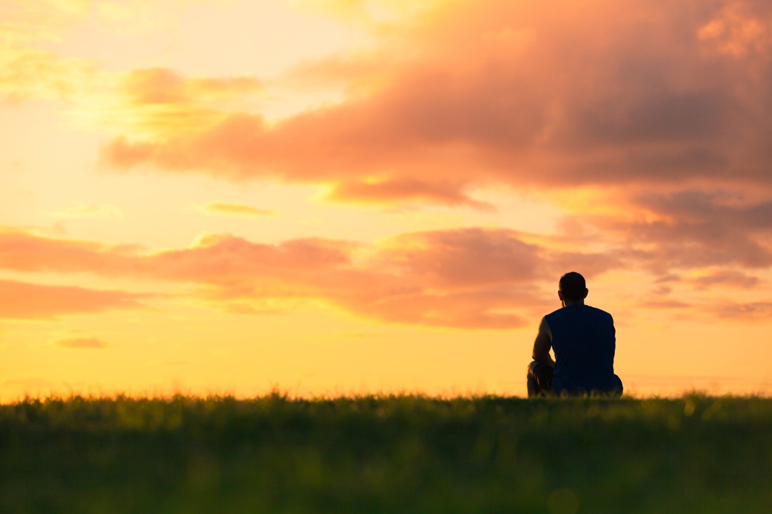 Man sitting on the grass and watching the sky